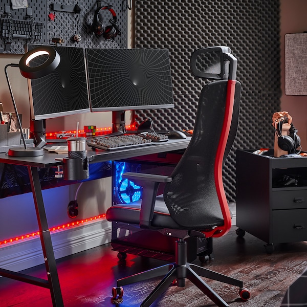 A black UTESPELARE gaming desk with two screens, a black gaming chair, a black drawer unit and various gaming accessories.