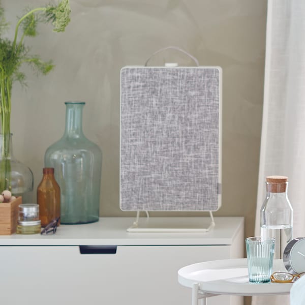 A FÖRNUFTIG air purifier on a white chest of drawers and a GLADOM tray table with an IKEA 365+ carafe and glass next to it.