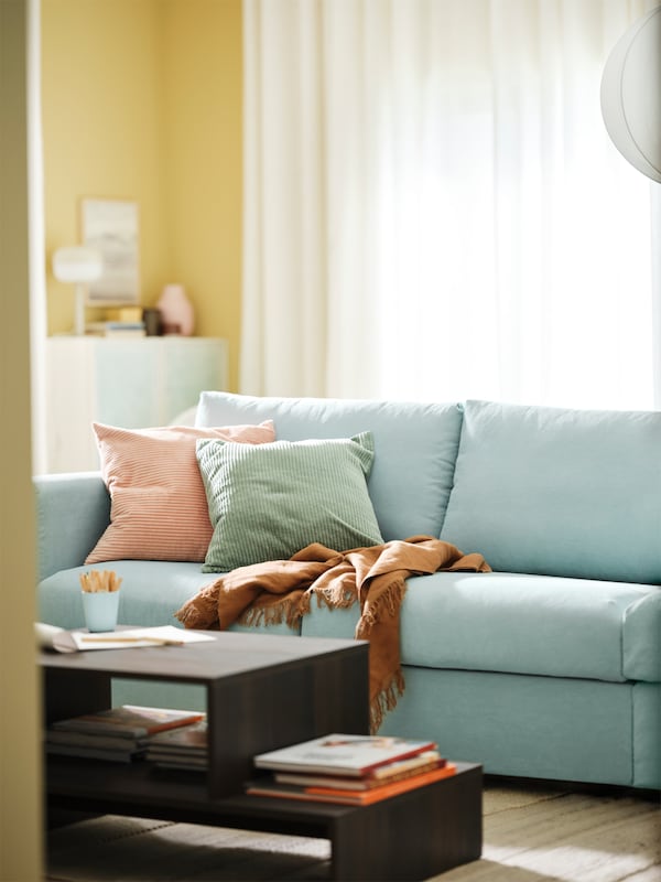 A light blue VIMLE 3-seat sofa bed and a HOLMERUD coffee table are in a bright living room with yellow walls.