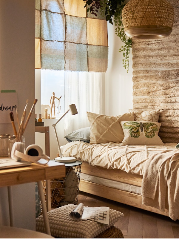 A rustic-style room with a pine UTÅKER stackable bed covered in NYPONLUGGMAL bed linen by a wall with a textured rug on it.