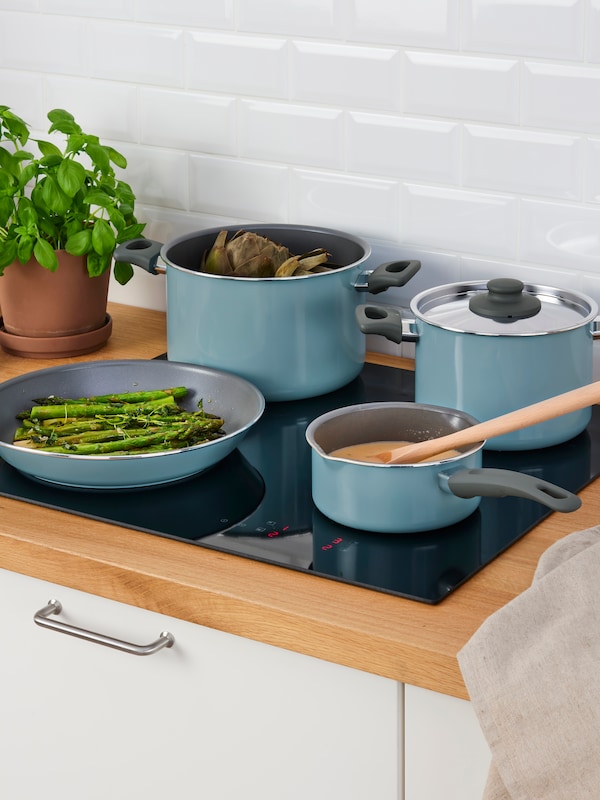 A set of HEMLAGAD pots and pans in blue colour on an induction hob.