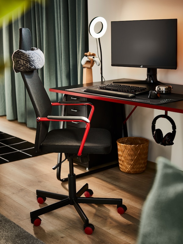 A tidy gaming space centred around a black HUVUDSPELARE desk, a black HUVUDSPELARE gaming chair and a LÅNESPELARE ring light.