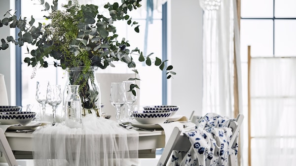 A wedding table decorated with a floral centrepiece, blue fabric backed TERJE chairs with a white traditional dining set.