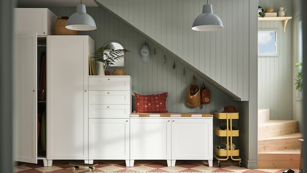 A white PLATSA series of wardrobes and cabinets are strategically placed in height order underneath a stairwell.