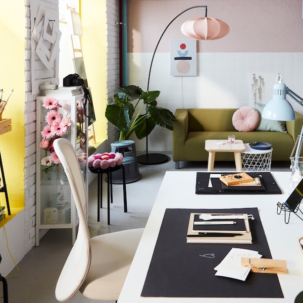 A workspace with a TROTTEN desk, a FLINTAN office chair and pink accents. At the back is a tall, curved floor lamp.