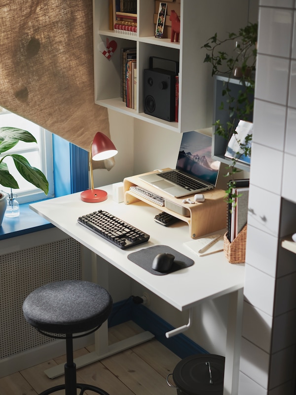A workspace with a TROTTEN sit/stand desk with a VATTENKAR laptop/monitor stand supporting a laptop on top of it.
