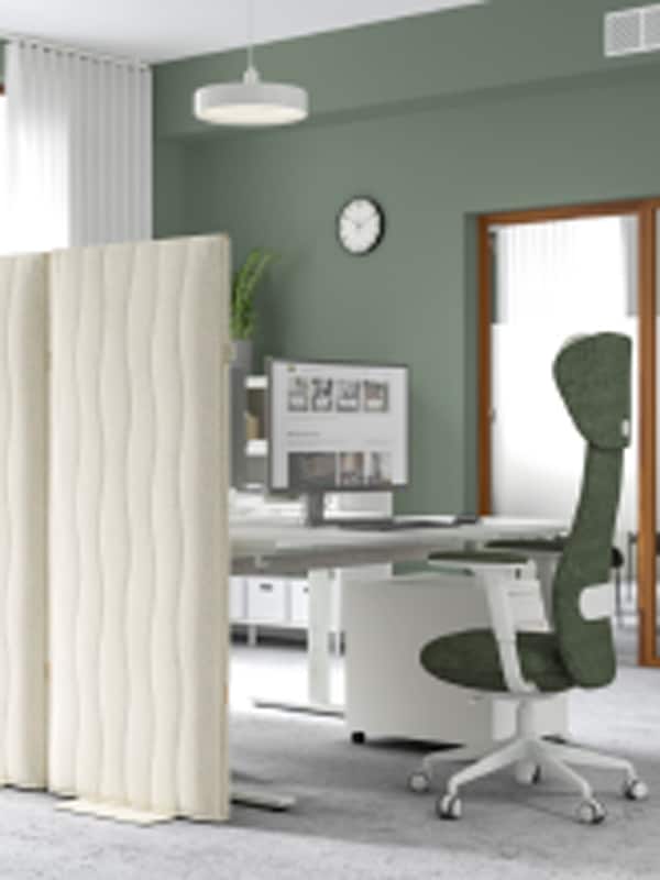A workstation in a modern office with green walls. There are two MITTZON acoustic screens in Gunnared beige.