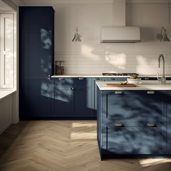 AXSTAD blue shaker kitchen with tall cabinet, white worktop, island and metal handles.
