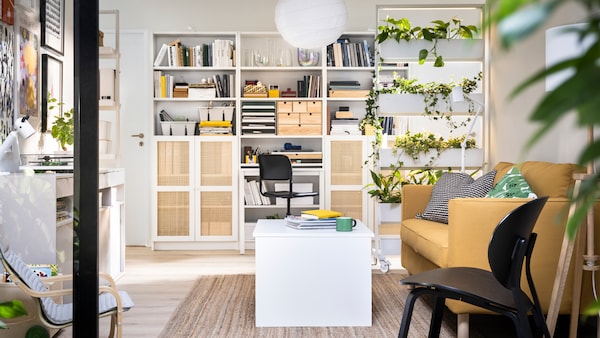 BILLY bookcases against a wall behind a MITTZON frame with castors and an ÖSTAVALL adjustable coffee table in a living room.