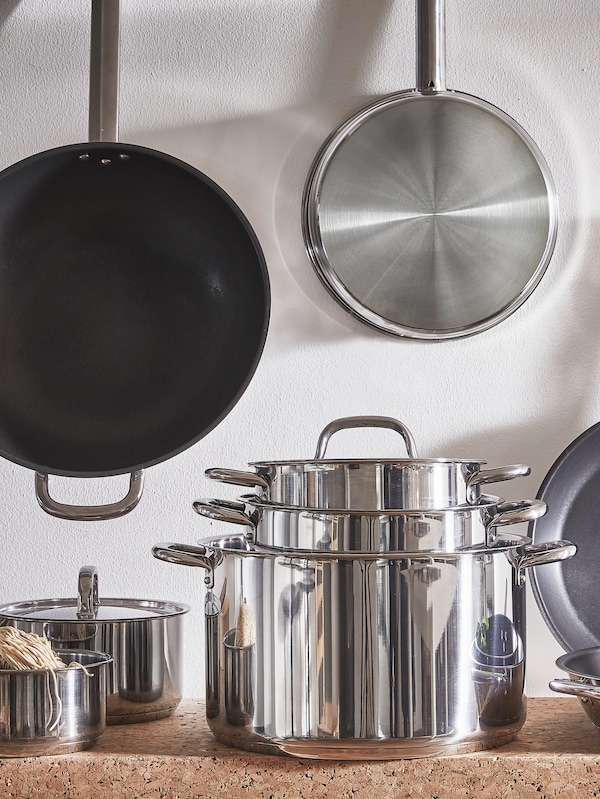 A set of IKEA 365+ cookware and matching frying pans hung on the wall.