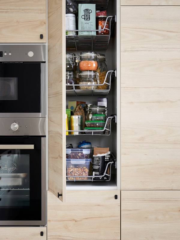 METOD high cabinet with the door open showing inside wire baskets one on top of the other filled with food.