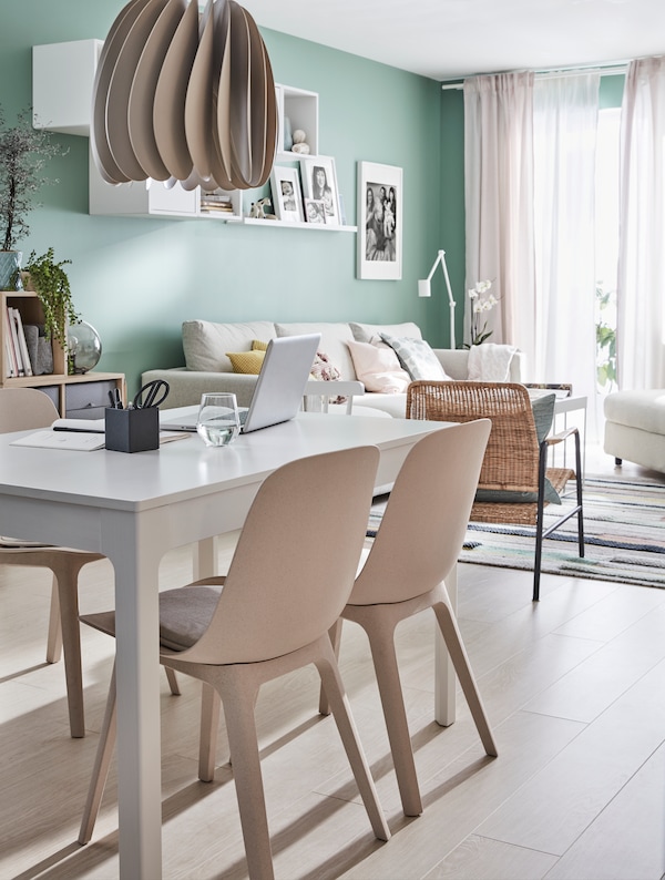 An IKEA EKEDALEN white dining table, beige dining chairs in a sunny living room with white floors and green walls