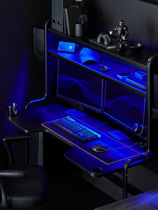 An IKEA FREDDE black gaming desk lit with blue neon lights.