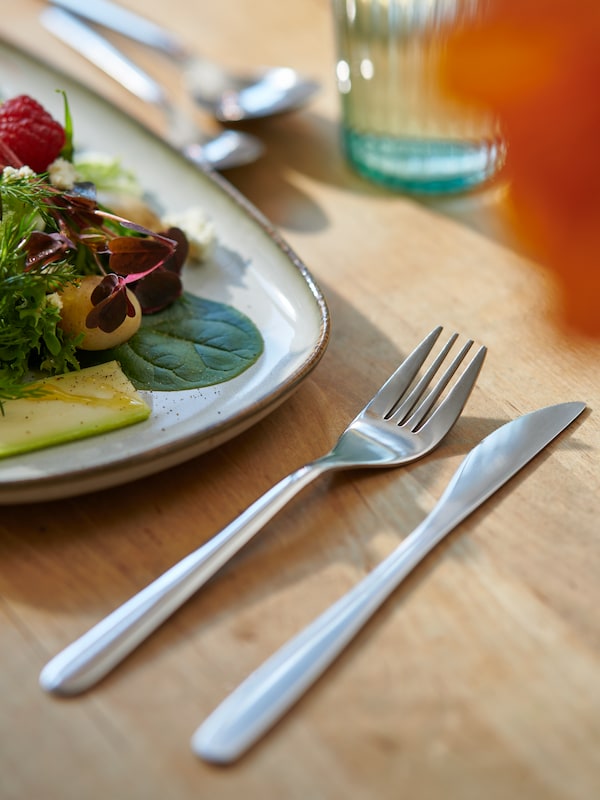 An IKEA set of FÖRNUFT cutlery on a dining table.