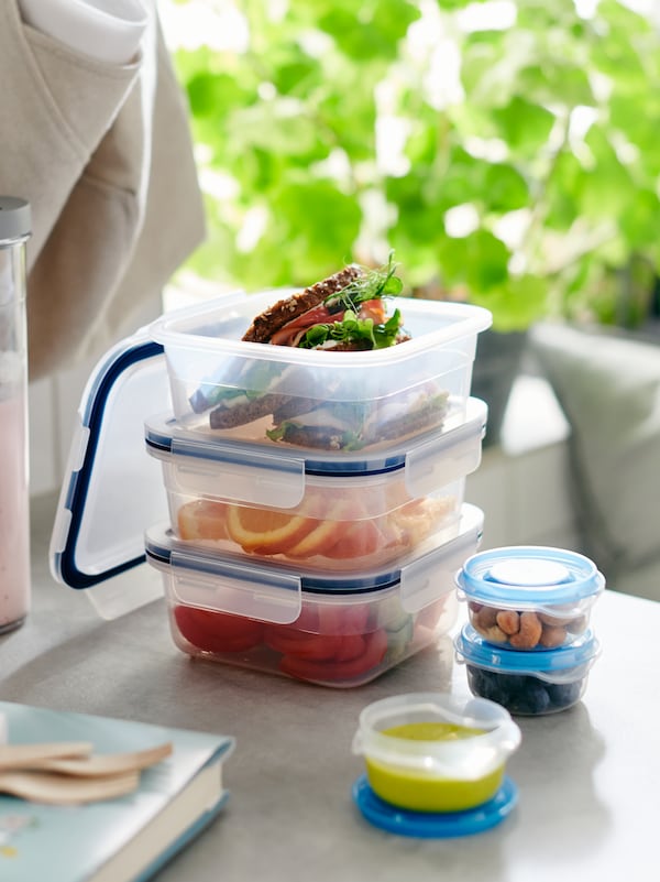 Three IKEA 365+ food containers with blue lids stacked on a table.