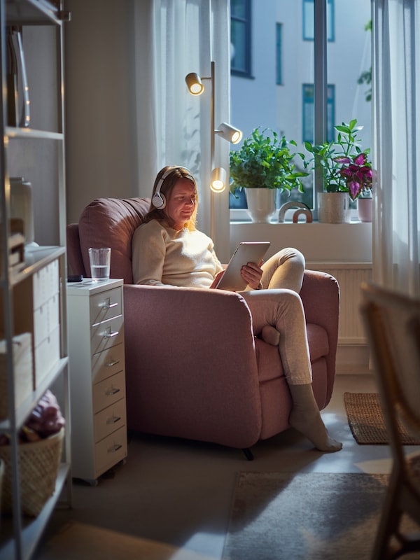 A person sitting on an EKOLSUND pink recliner armchair playing on a table, in a room with dimmed lighting.