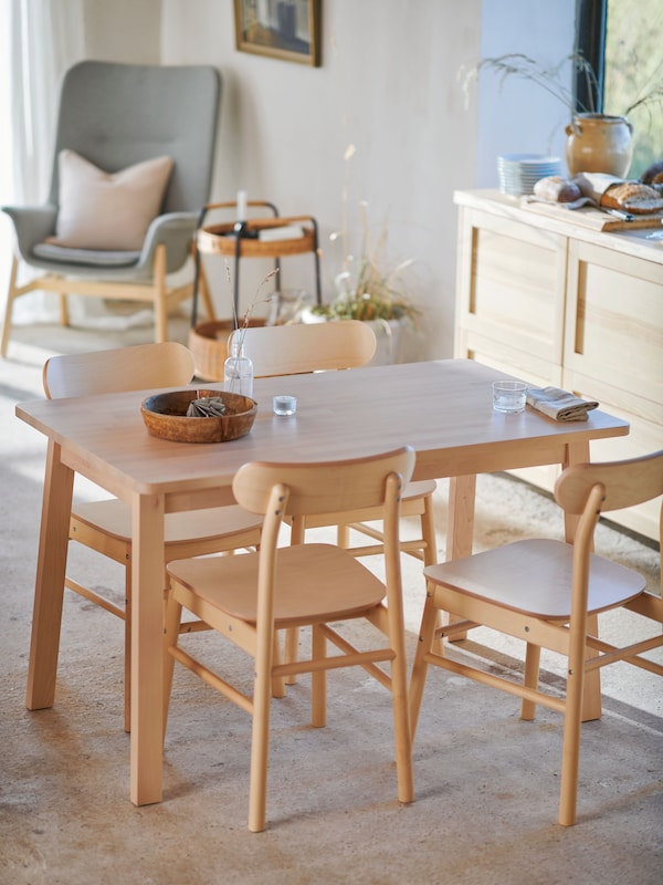 A sunny kitchen with an IKEA RÖNNINGE dining table in ash cokour, a bench and dining chairs the same finish.