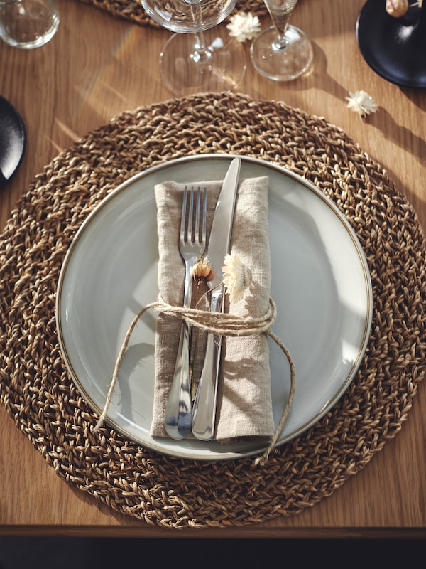 An IKEA GLADELIG plate in beige over a jute place mat