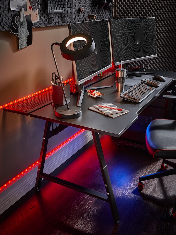 An IKEA UPPSPEL black gaming desk in a room lit with red neon lights.