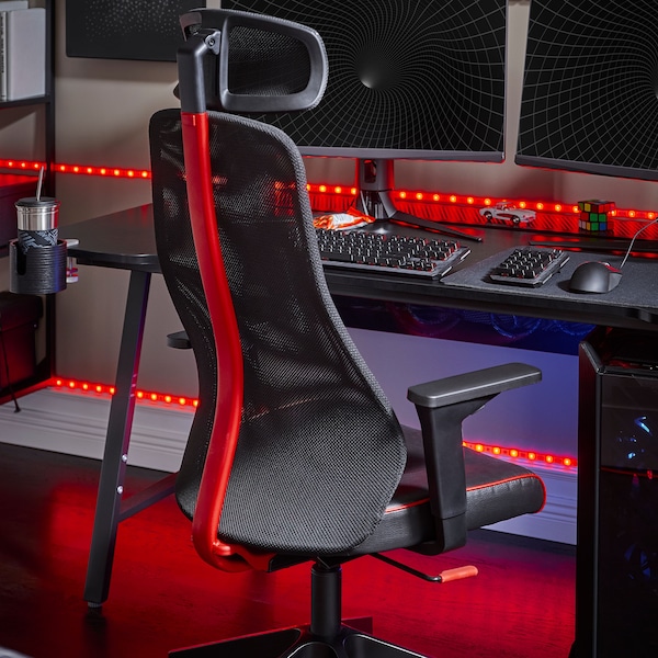 An IKEA MATCHSPEL gaming chair in black and red in front of a black gaming desk lit with red neon lights.