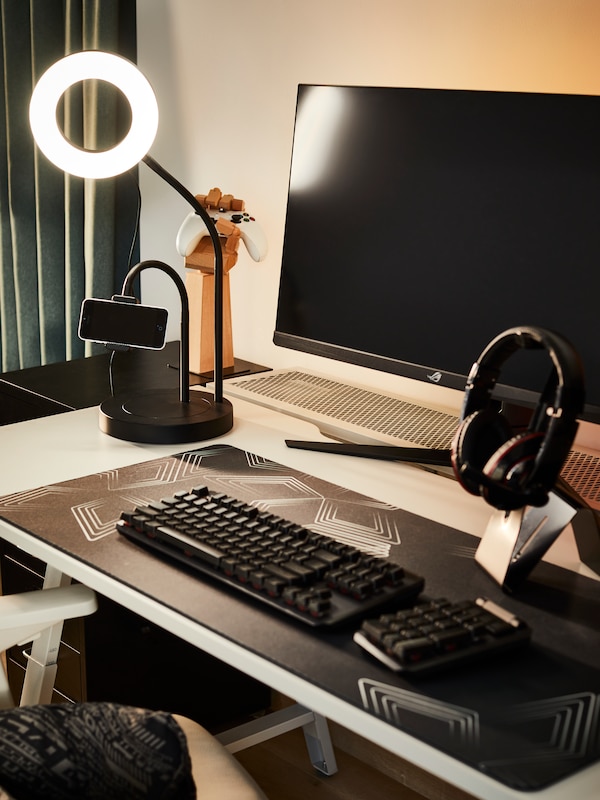 An IKEA white desk with a lit LÅNESPELARE ring light, a keyboard and a screen on it.