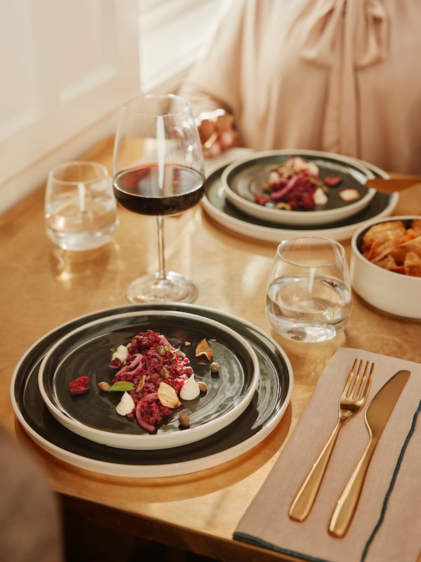 A wood dining table set with blue and white plates and DYRGRIP glasses.