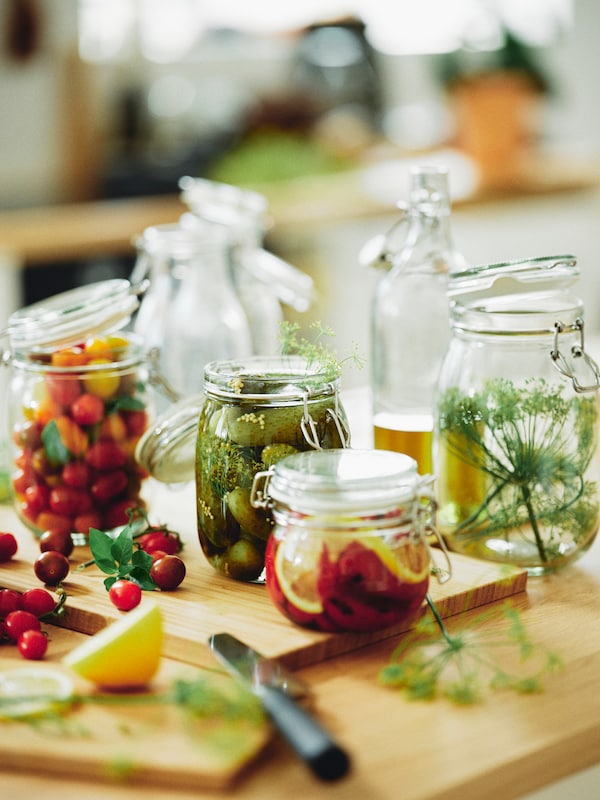 IKEA KORKEN glass jars filled with various vegetables on a wooden chopping board.