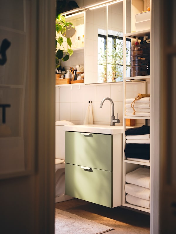 ENHET modern bathroom combination with open and close wall cabinet with mirror doors and base cabinet with green drawer fronts.