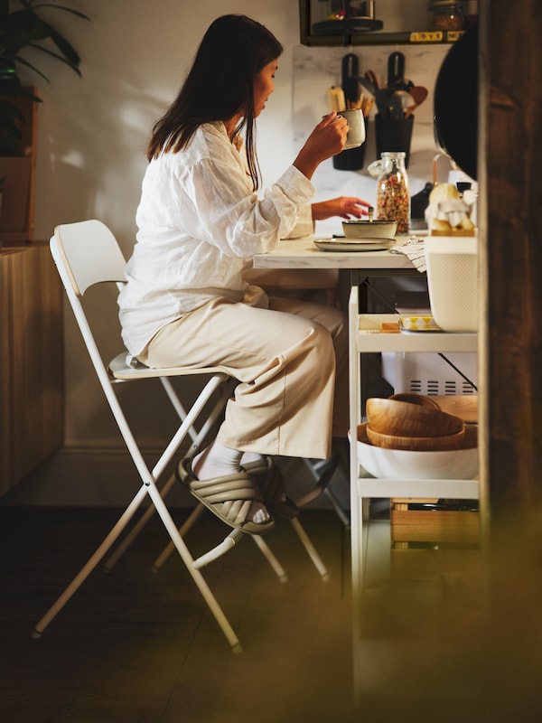 A person sitting on an IKEA FRANKLIN white bar stool having breakfast