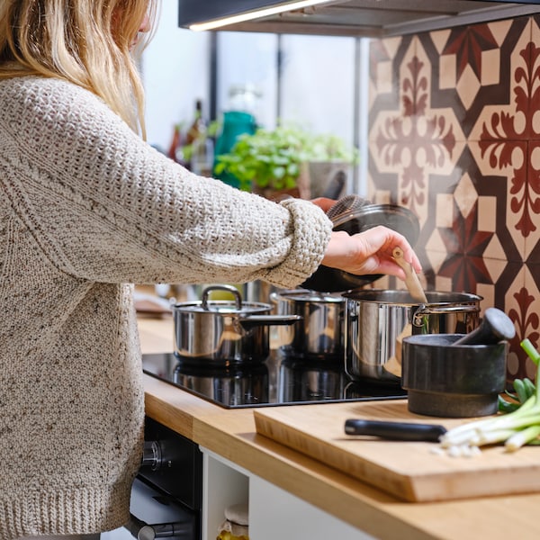 A person using IKEA 365+ cookware on a MATMÄSSIG induction hob .