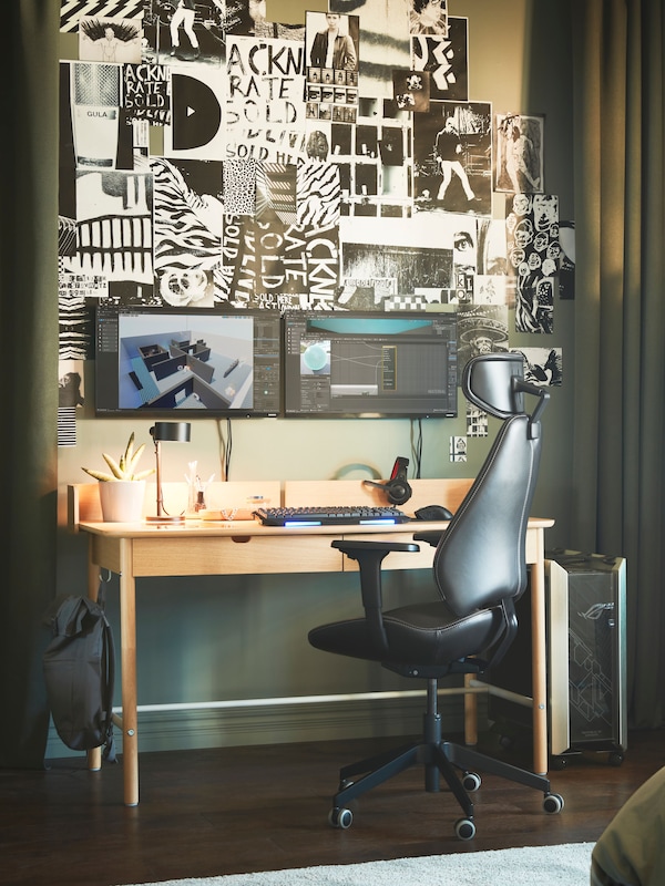 A gaming station between two green curtains. There is a picture wall with illustrations above a RIDSPÖ desk with screens.