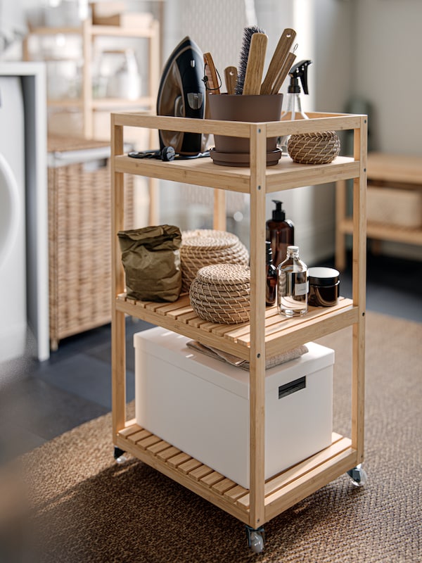 A RÅGRUND trolley containing different storage boxes in a bathroom, with a low pile rug