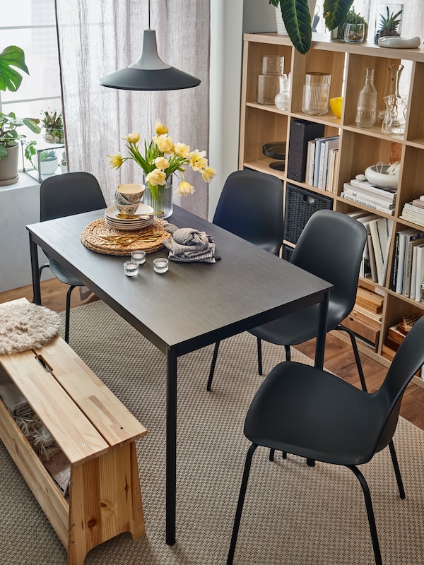 A rectangle IKEA SANDSBERG dining table in black brown with four matching chairs, various party craft supplies on top
