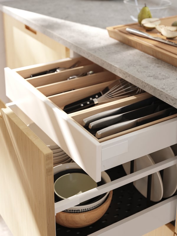 MAXIMERA kitchen drawer half open to show another kitchen drawer hidden inside and UPPDATERA bamboo and black plastic interior organisers.