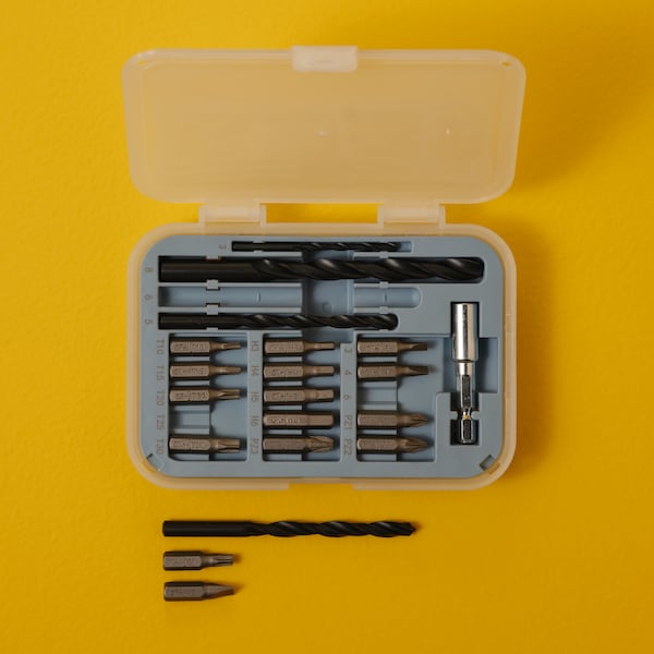 A TRIXIG 20-piece bit and drill set placed on a bright yellow surface.