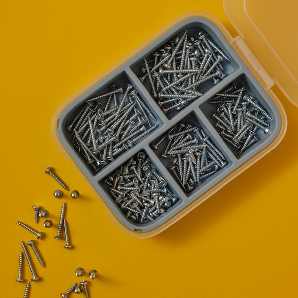 A TRIXIG 200-piece wood screw set on a bright yellow surface. Some screws, of different sizes, are scattered on the surface.