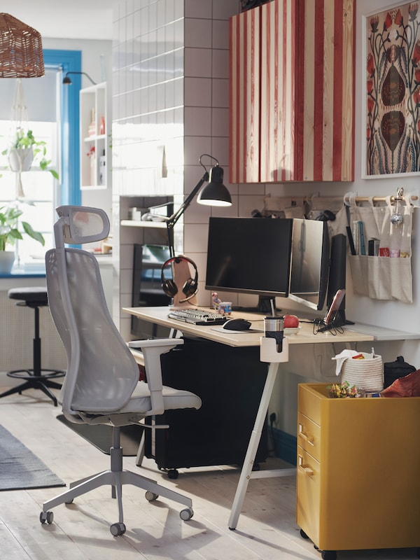 An office and gaming setup with an UTESPELARE gaming desk, MATCHSPEL gaming chair and a cabinet painted in a striped pattern.