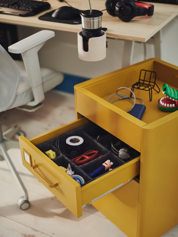 An IKEA IDÅSEN drawer unit on castors beside a gaming desk.