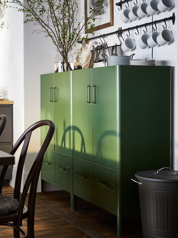 An IKEA IDÅSEN bright green filing cabinets in a room with dark wood flooring and white walls.