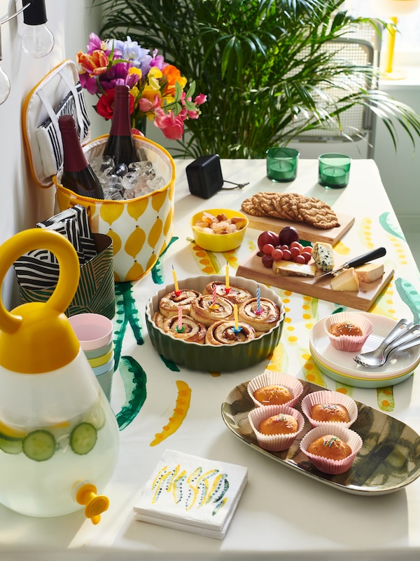 Various IKEA NÄBBFISK ovenware and serveware on a table filled with food, jars and cooling bag.