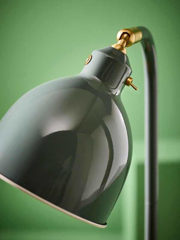 Close up of RÖDFLIK reading lamp on green background