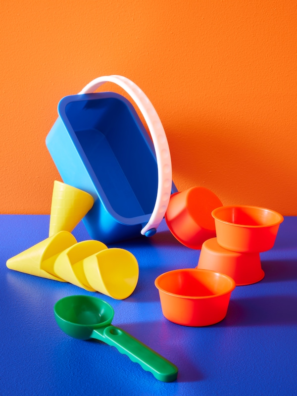 A SANDIG 10-piece sand ice cream set of toys arranged in a space with an electric blue floor and orange walls.