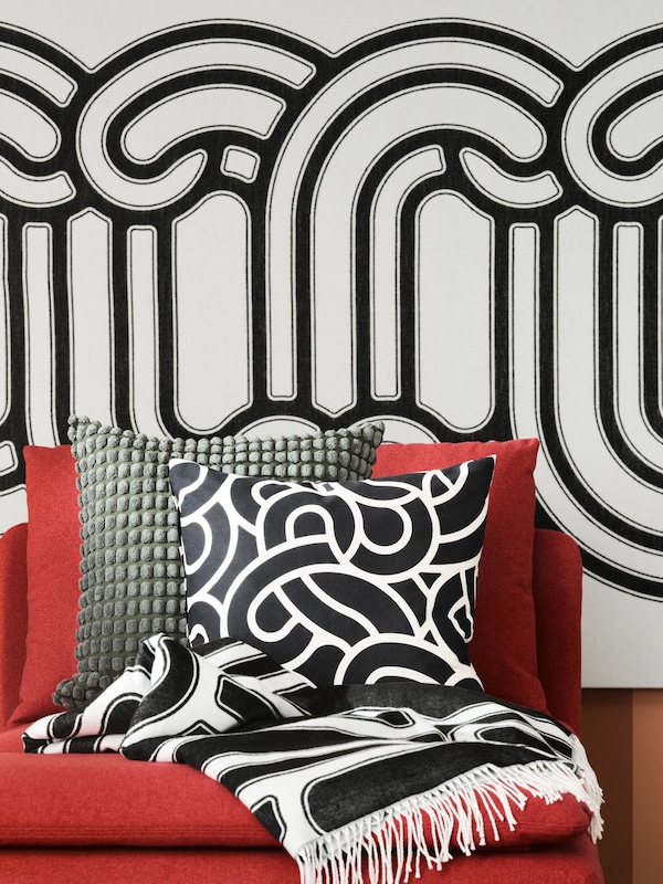 A close up of a red SÖDERHAMN sofa with SVARTPOPPEL cushions and SÖTRÖNN wall art