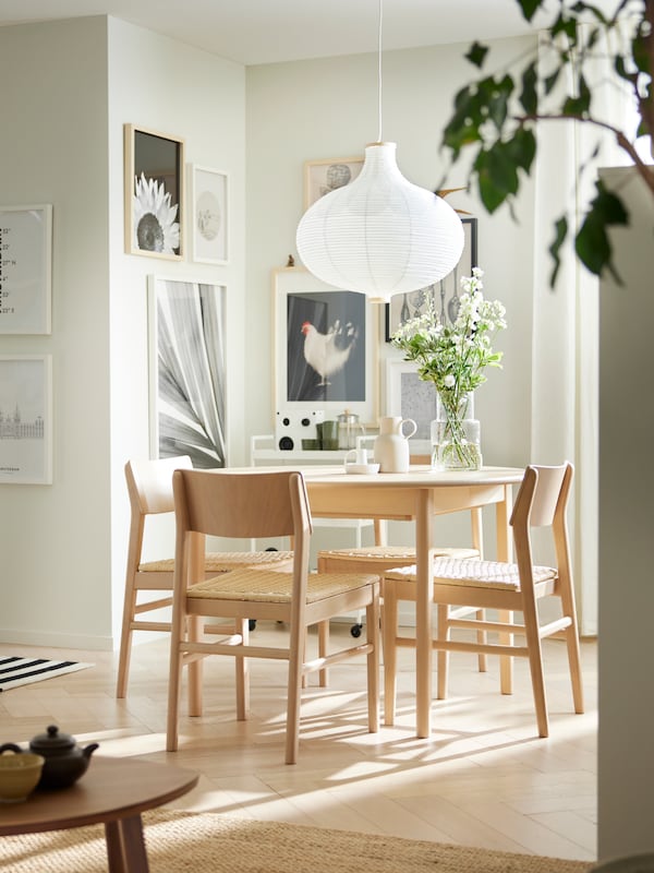 A SKANSNÄS round extendable table and four SKANSNÄS light beech chairs stand under a white RISBYN pendant lamp.