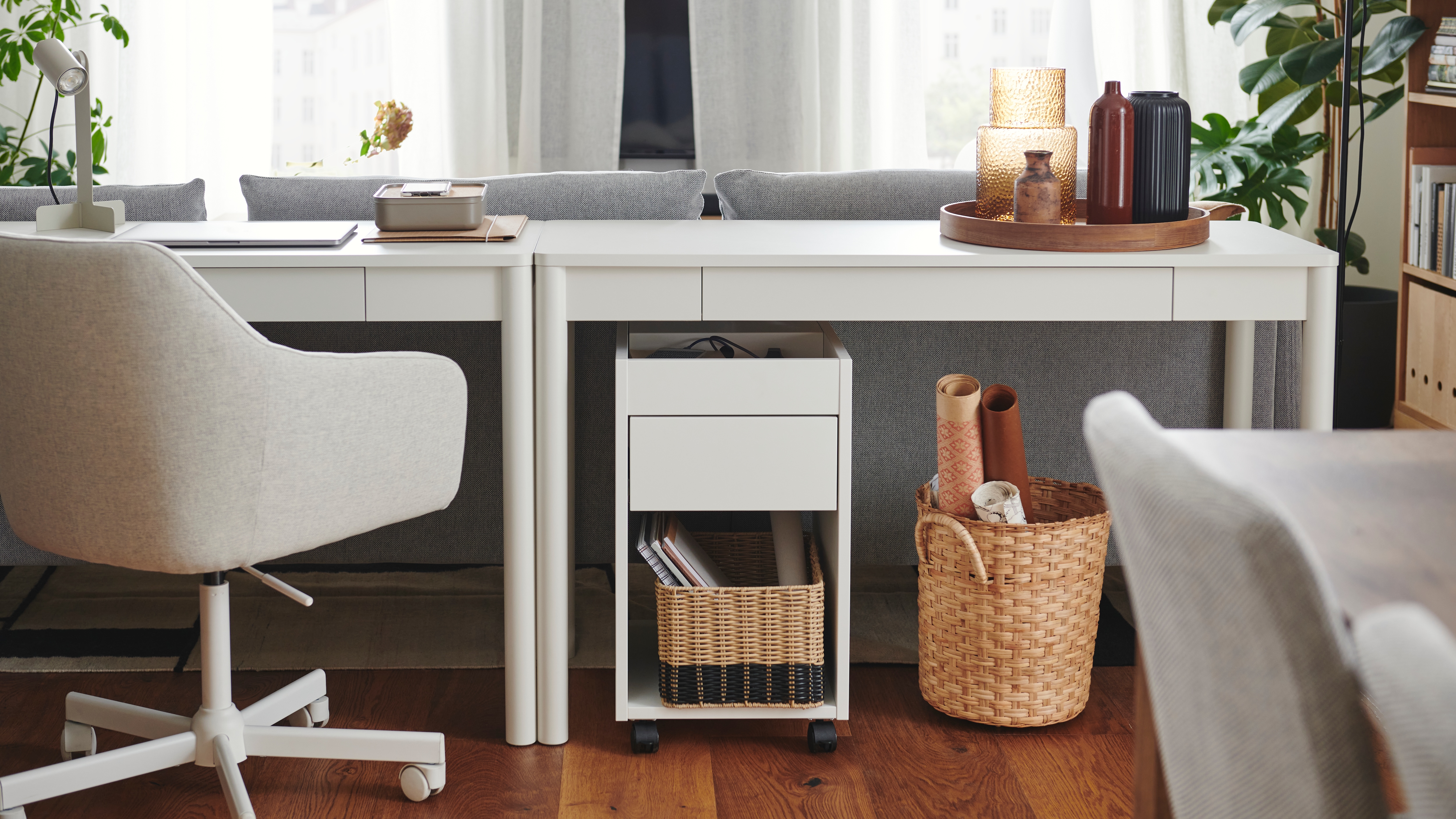 A bright room. A workspace with a TONSTAD desk is placed on the back of a grey sofa.