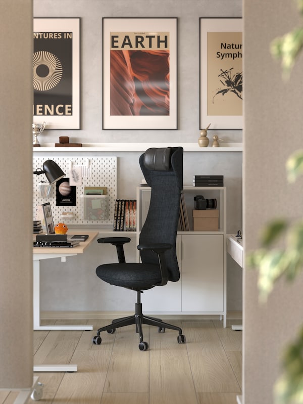 A workstation featuring beige walls, wooden floors, art posters, and a GRÖNFJÄLL office chair in Letafors grey/black.