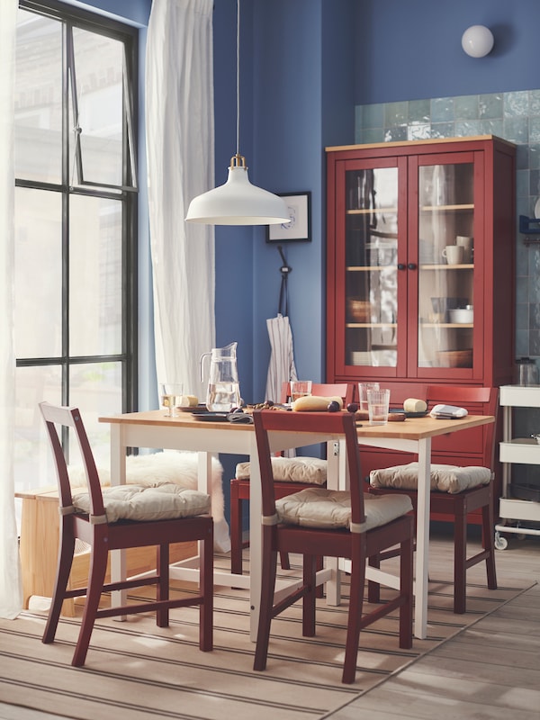 Red-stained PINNTORP chairs and a PINNTORP gateleg table are in a Swedish cottage-style dining room with blue walls.