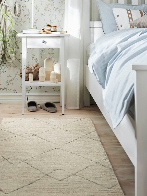 TVERSTED beige low pile rug shown near the bed and bedside table.